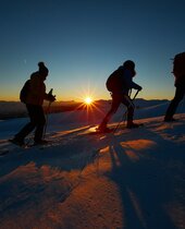 Gruppe beim Schneeschuhwandern in Matrei in Osttirol bei Sonnenuntergang